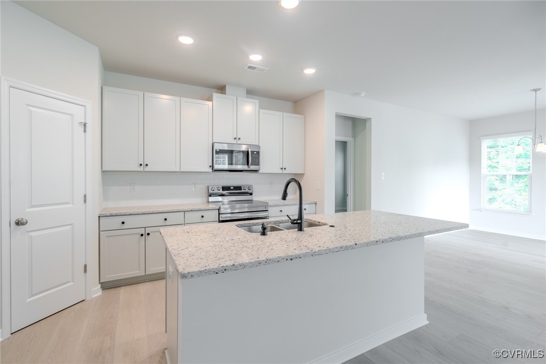 a kitchen with a sink white cabinets and stainless steel appliances