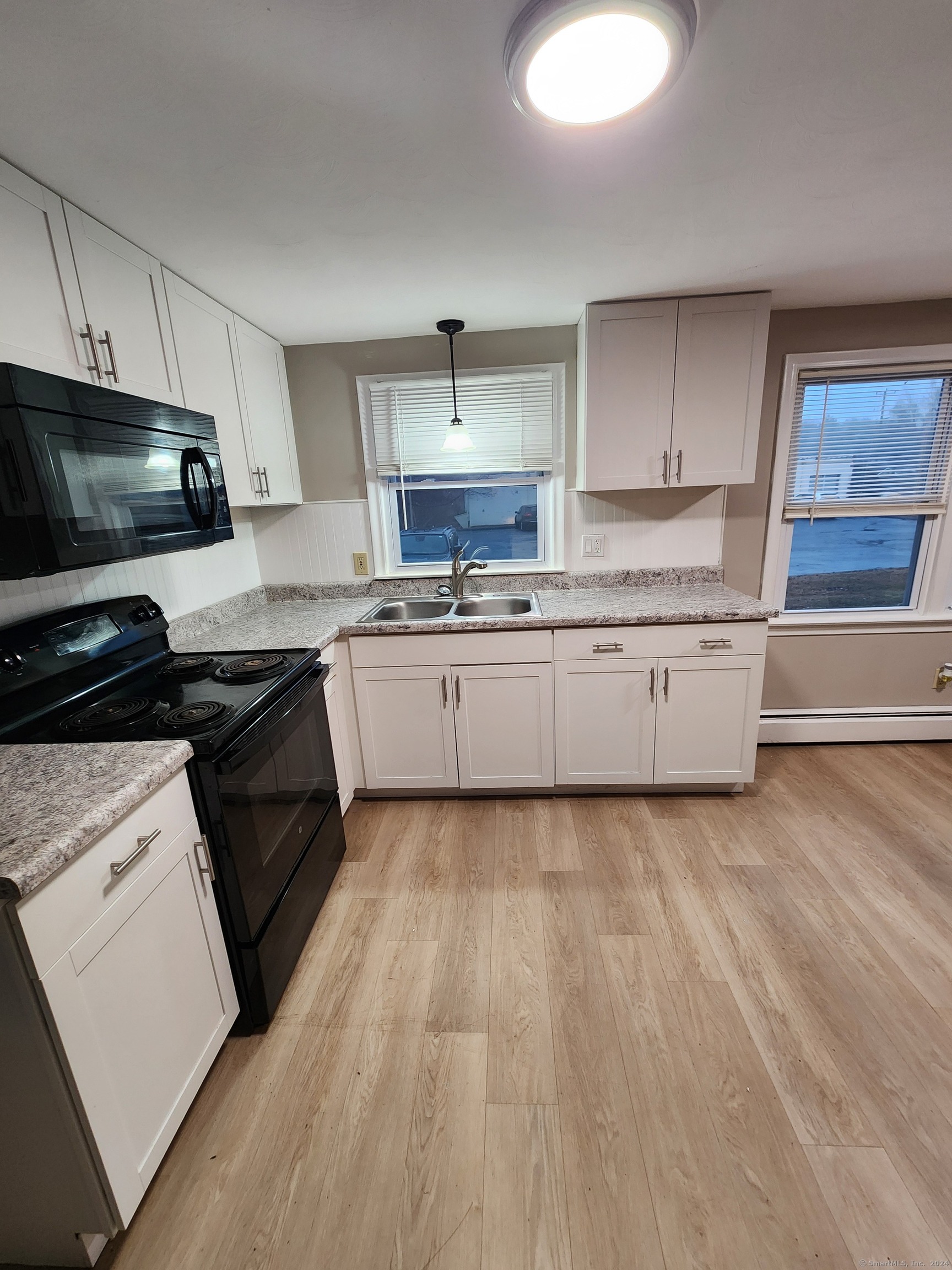 a kitchen with granite countertop a stove top oven a sink dishwasher and white cabinets