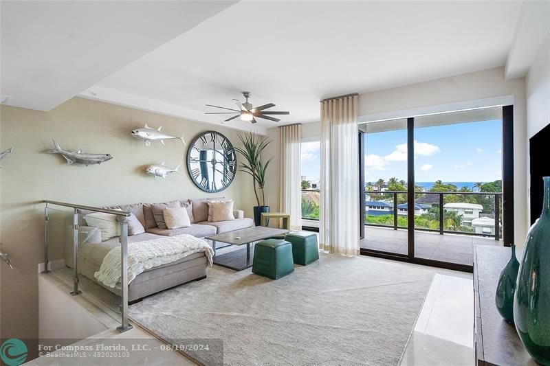 a living room with couch a large window and a chandelier