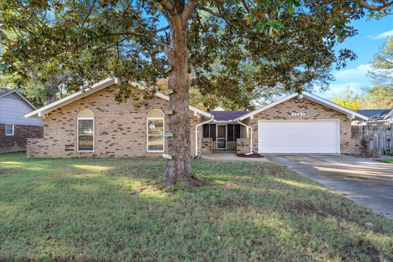 Single story home with a garage and a front lawn