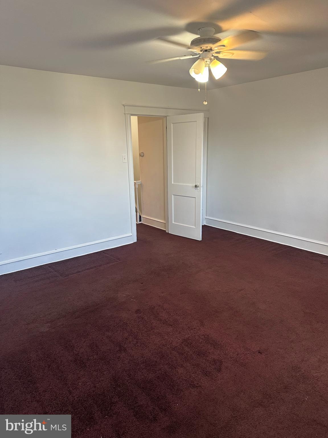 a view of an empty room and chandelier fan