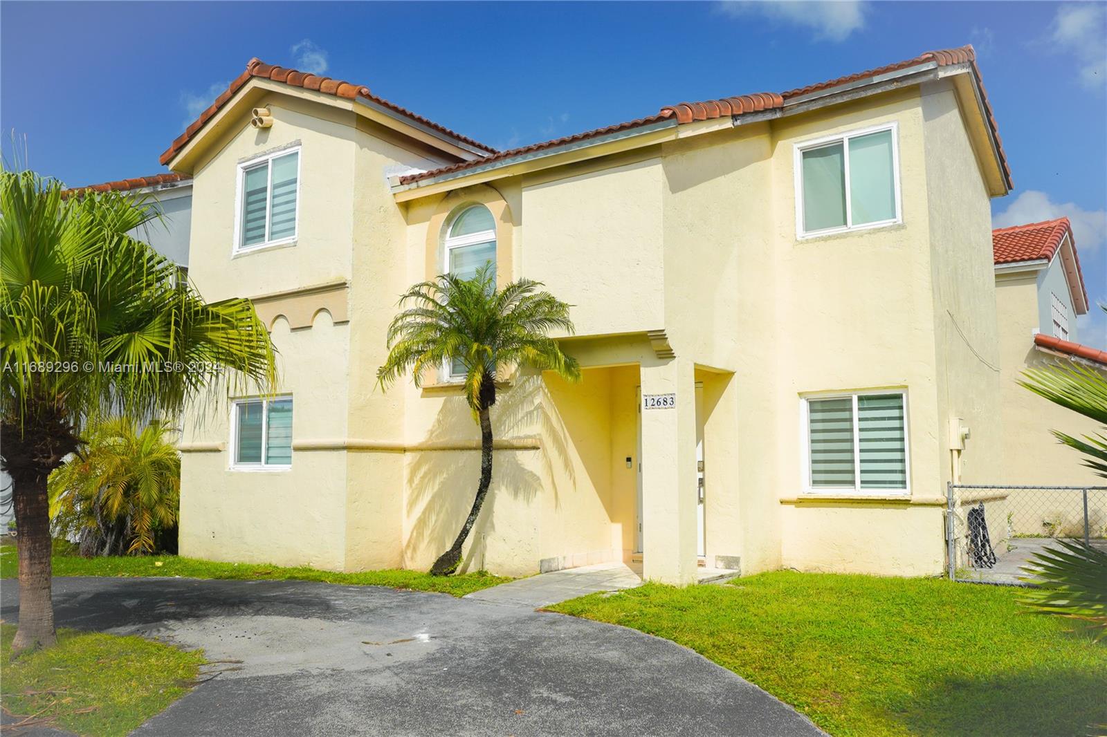 a house with a yard plants and palm trees