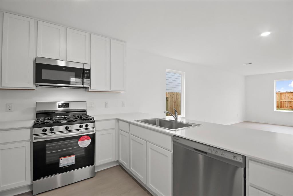 a kitchen with granite countertop a sink a stove and microwave