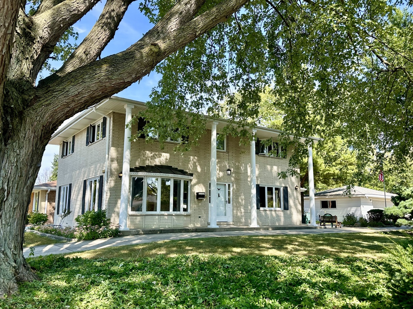 a view of a white house with a big yard and large trees