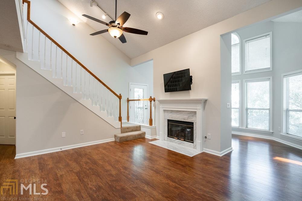 a view of an empty room with wooden floor fireplace and a window