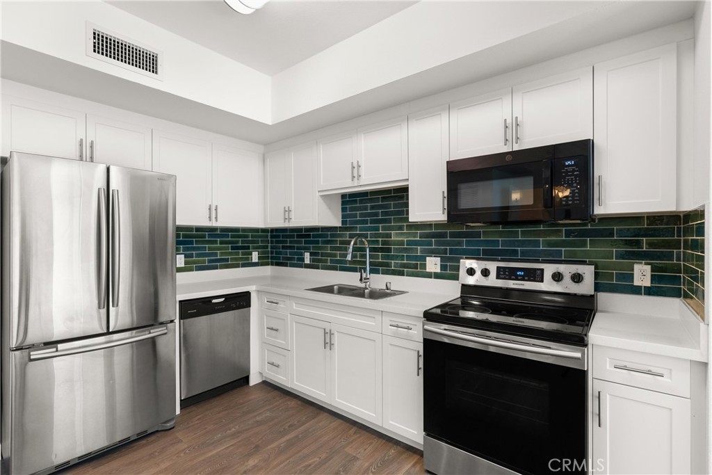 a kitchen with cabinets stainless steel appliances and wooden floor