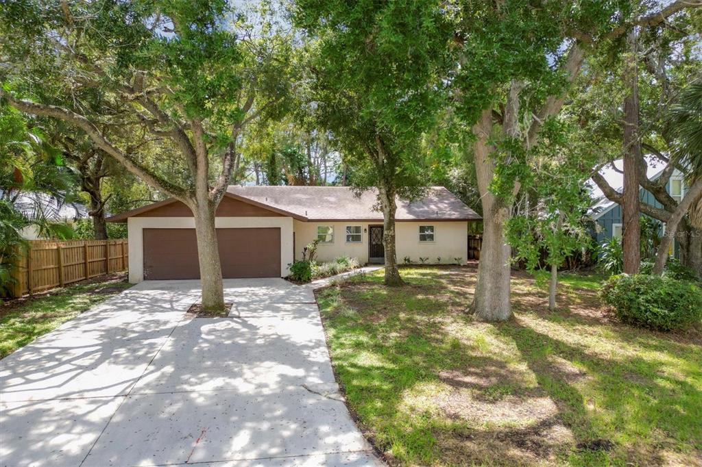 a view of a house with a yard and large tree