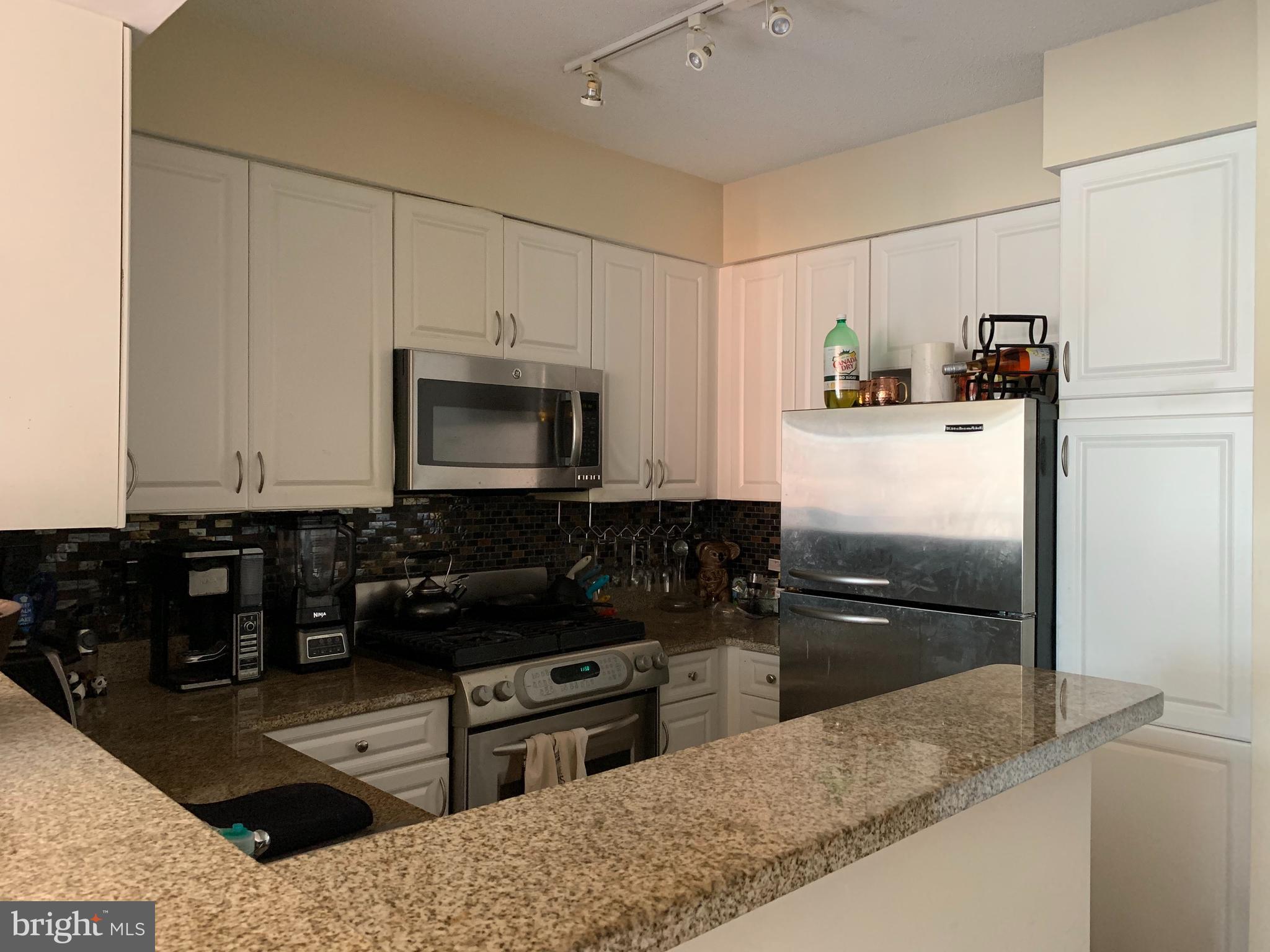 a kitchen with granite countertop a refrigerator stove and sink