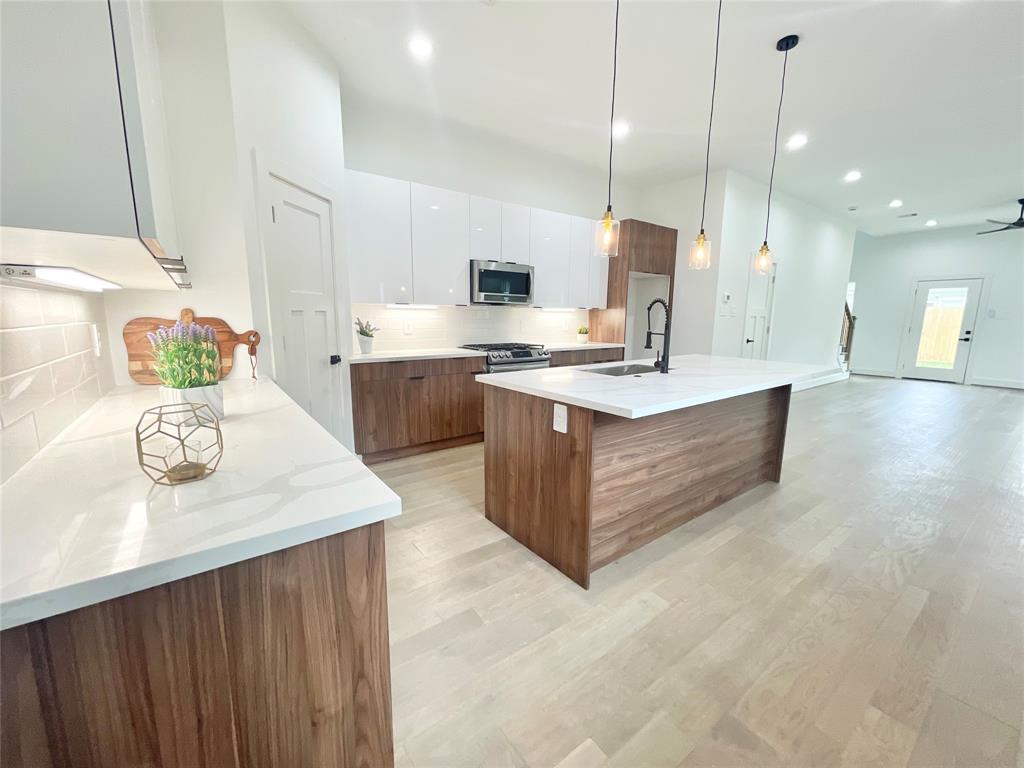 a kitchen with stainless steel appliances granite countertop a sink a stove and a wooden floor