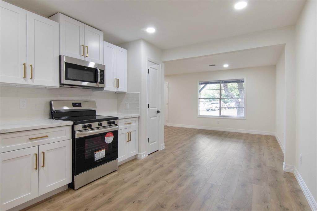 a kitchen with stainless steel appliances granite countertop a stove a microwave a sink and cabinets