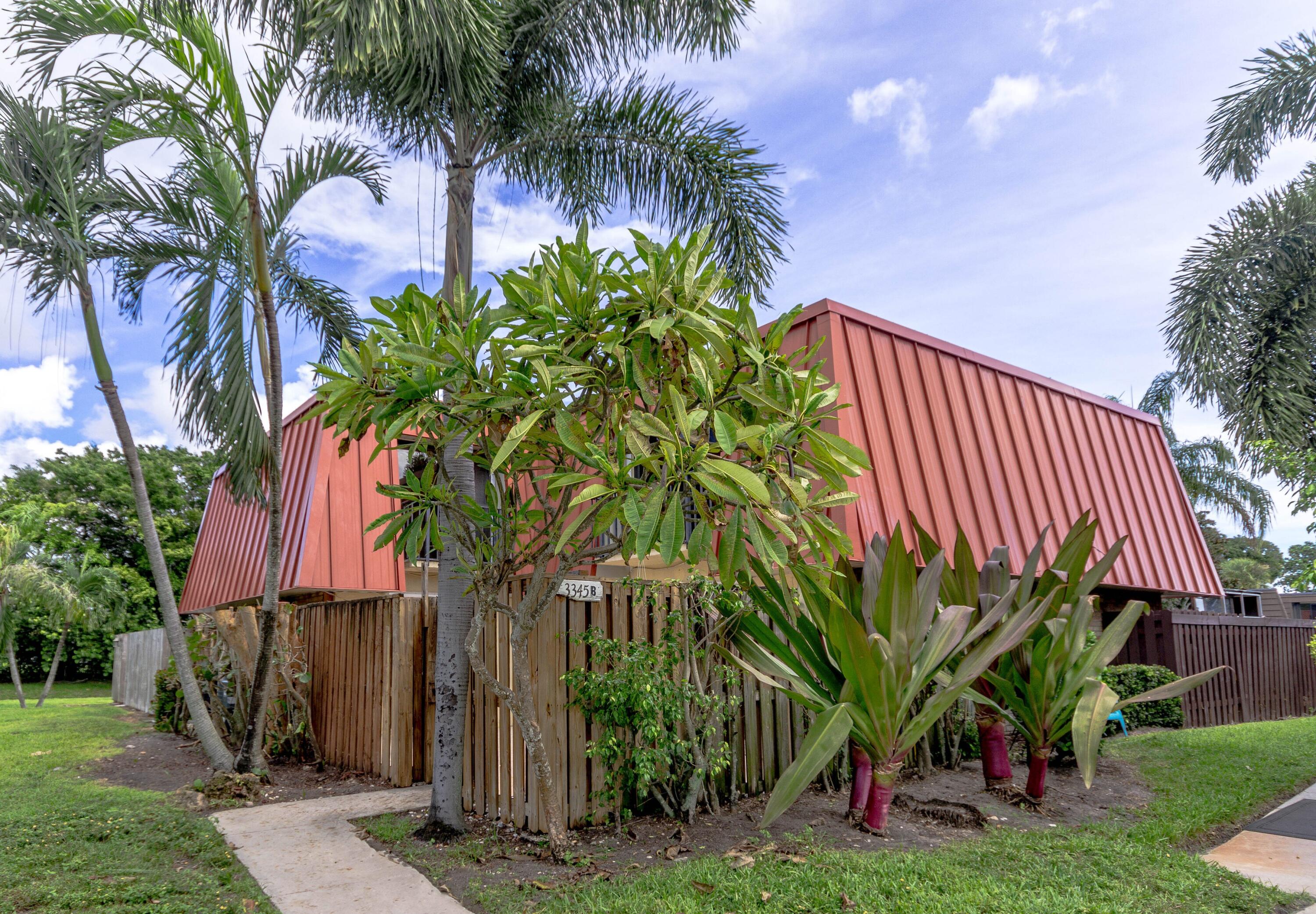 a palm tree sitting in front of a house with a yard