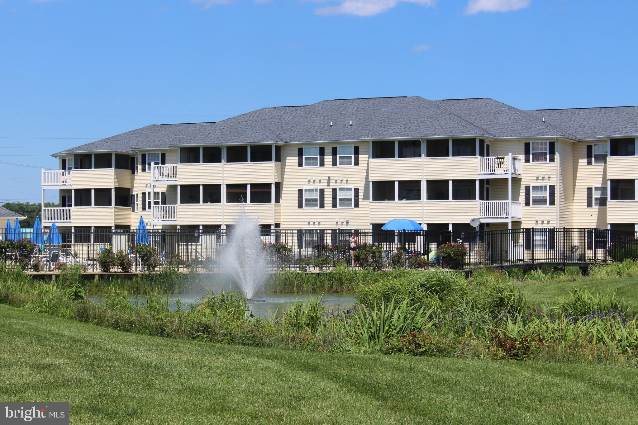 a front view of a building with garden and trees