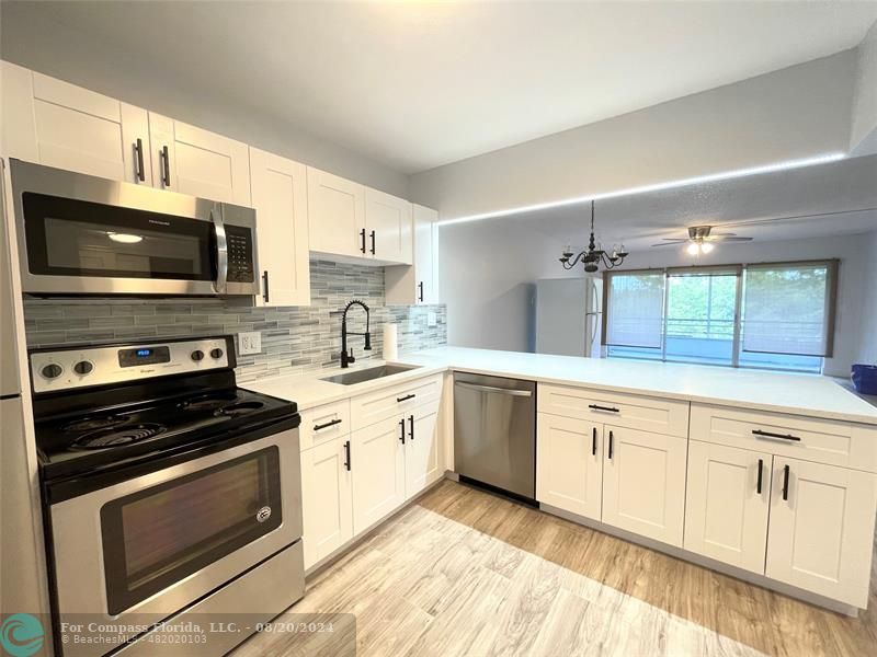 a kitchen with granite countertop a stove top oven microwave and cabinets