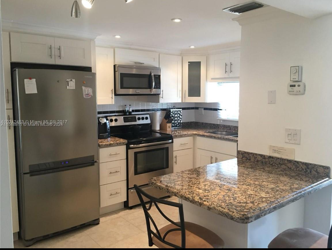 a kitchen with stainless steel appliances granite countertop a refrigerator sink and stove