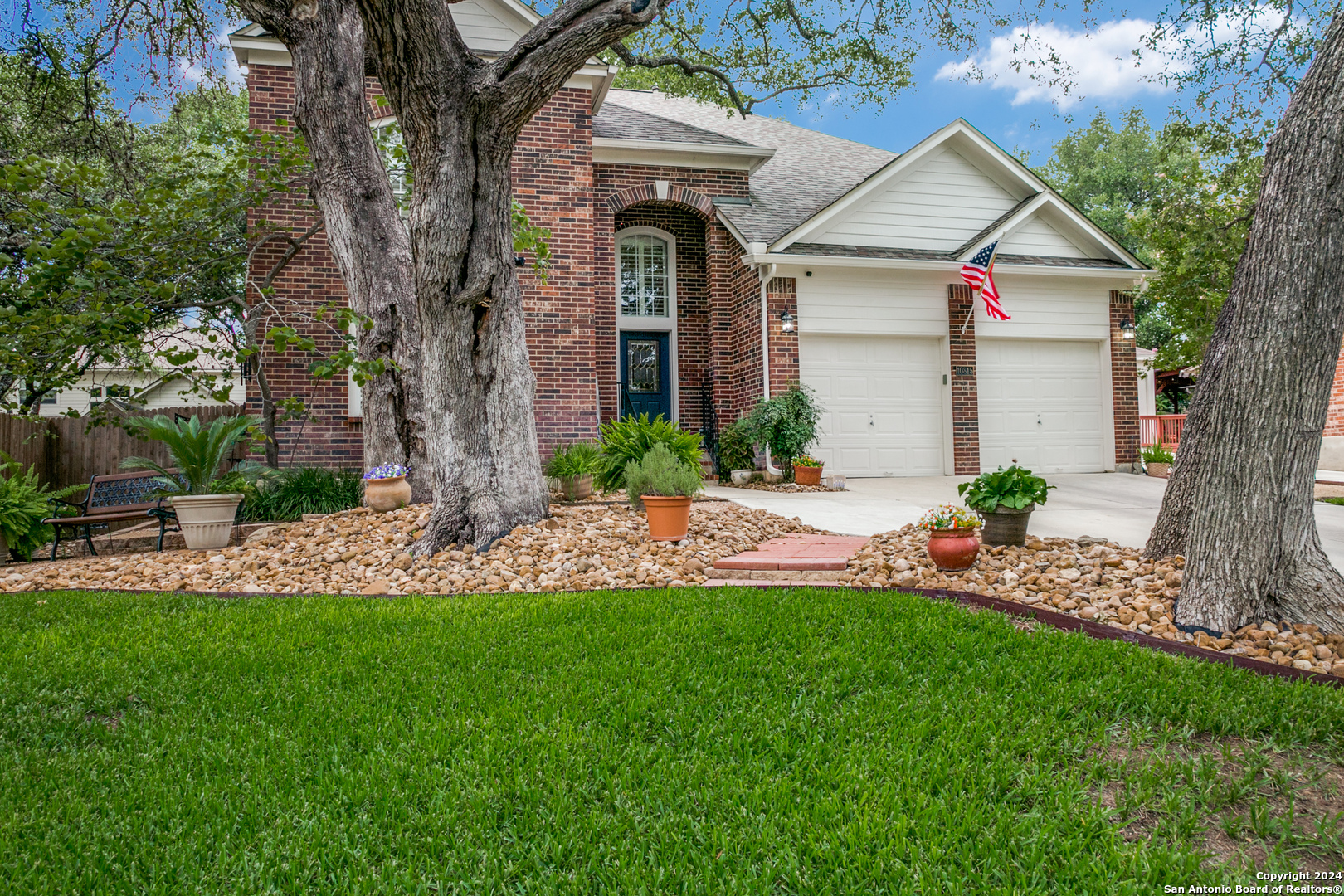 a front view of a house with a yard and large tree