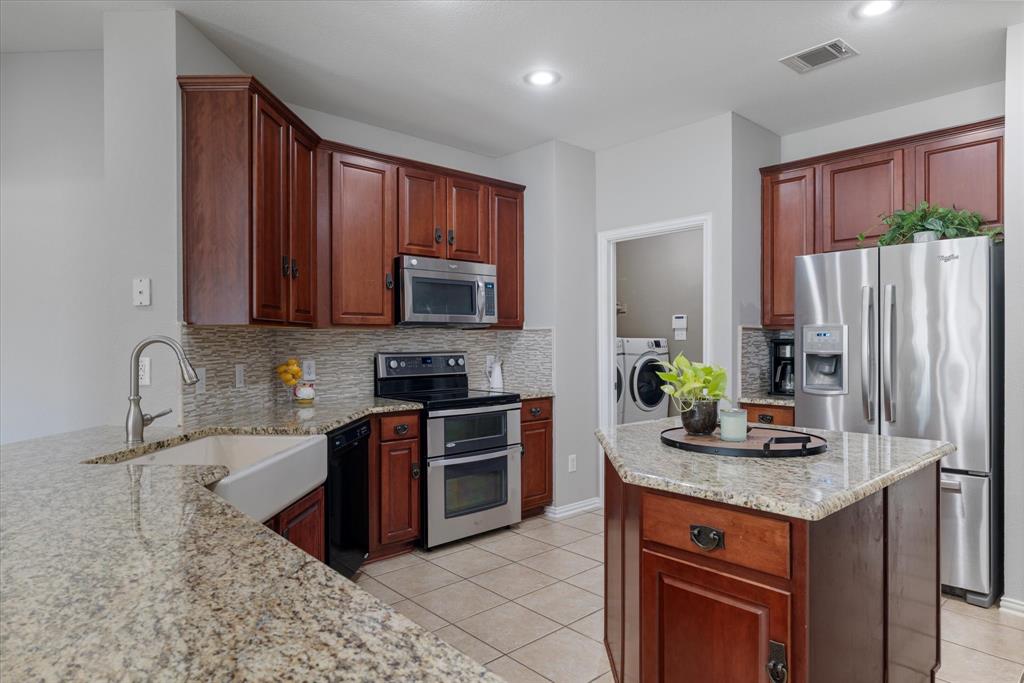 a kitchen with stainless steel appliances granite countertop a stove a sink dishwasher a refrigerator and a microwave