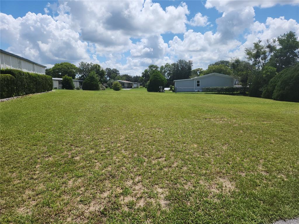 a view of a green field with house in the background