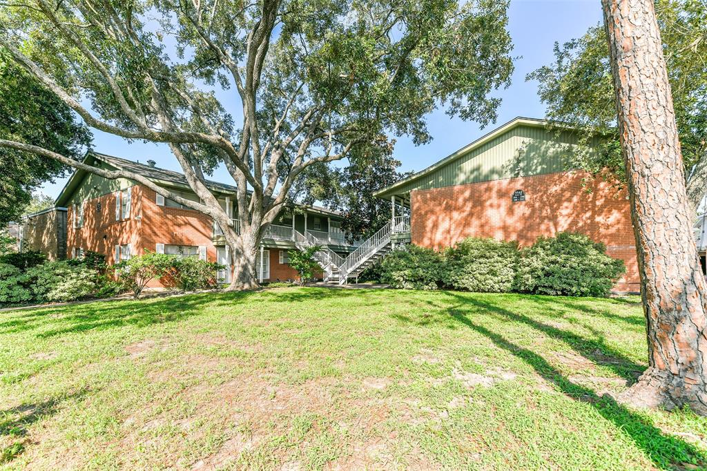 This is a two-story brick building with an elevated main entrance accessible by a staircase, surrounded by mature trees and green lawn.