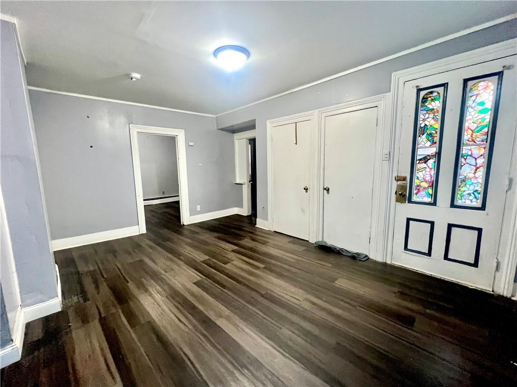 Unfurnished bedroom featuring ornamental molding, dark hardwood / wood-style flooring, and two closets