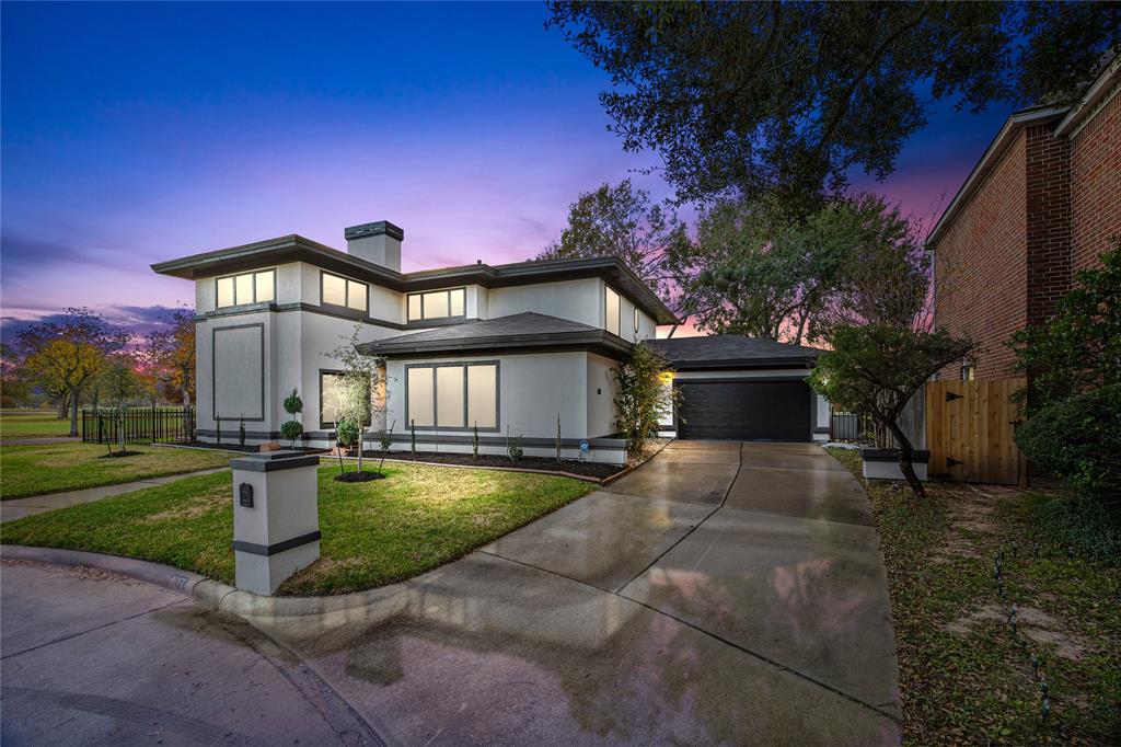 This modern two-story home features clean lines and large windows. It is nestled on a well-maintained lot with a spacious driveway and attached garage, set against a serene twilight backdrop.