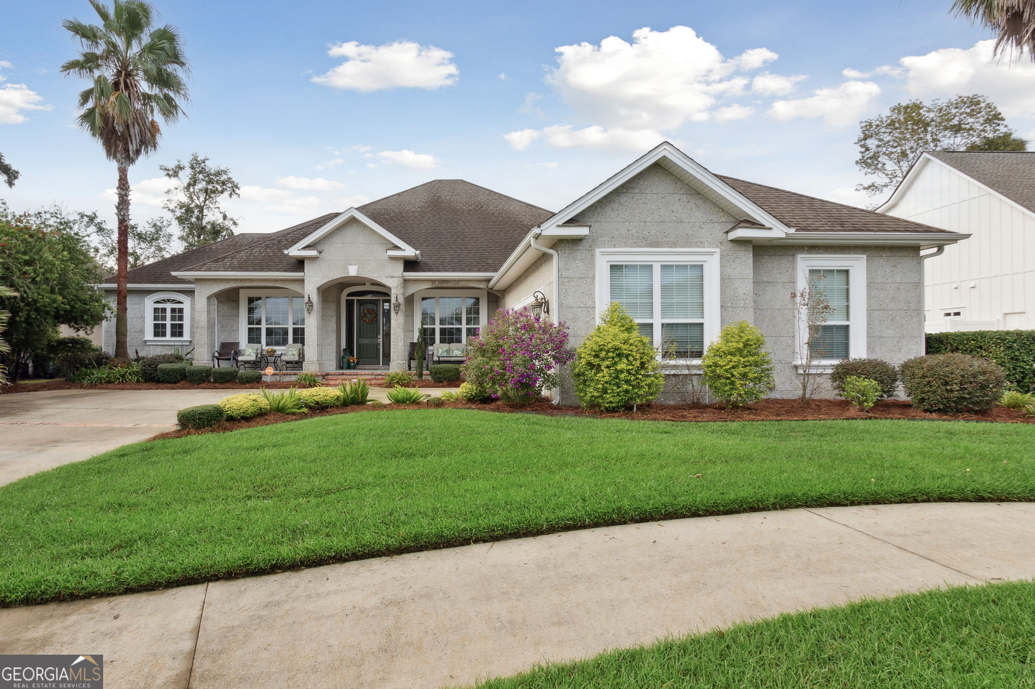 a front view of a house with a yard and potted plants