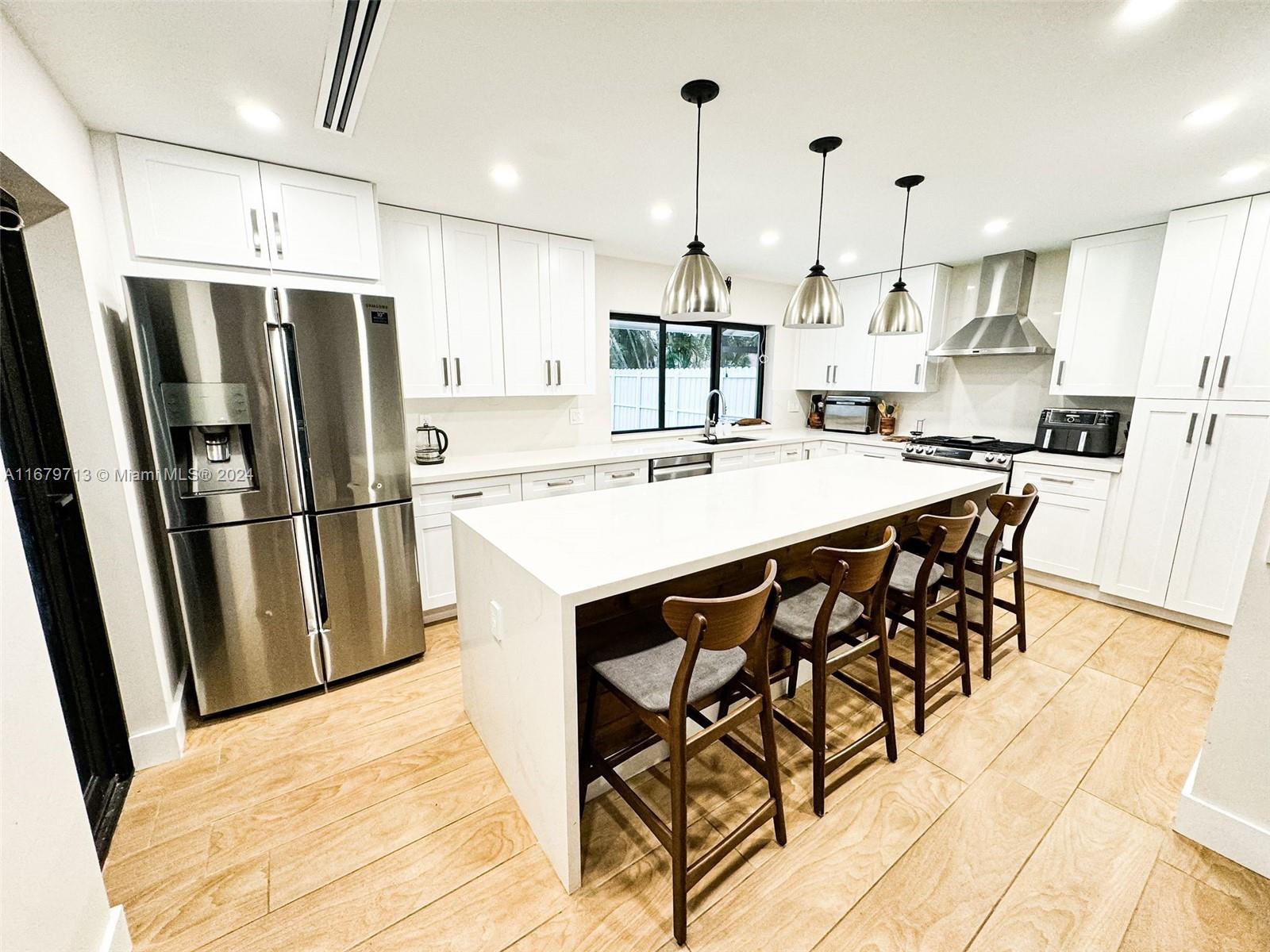 a kitchen with stainless steel appliances a dining table chairs stove refrigerator and cabinets