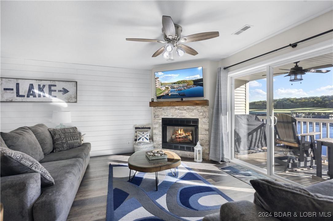 living room with lvp flooring, stone fireplace, an