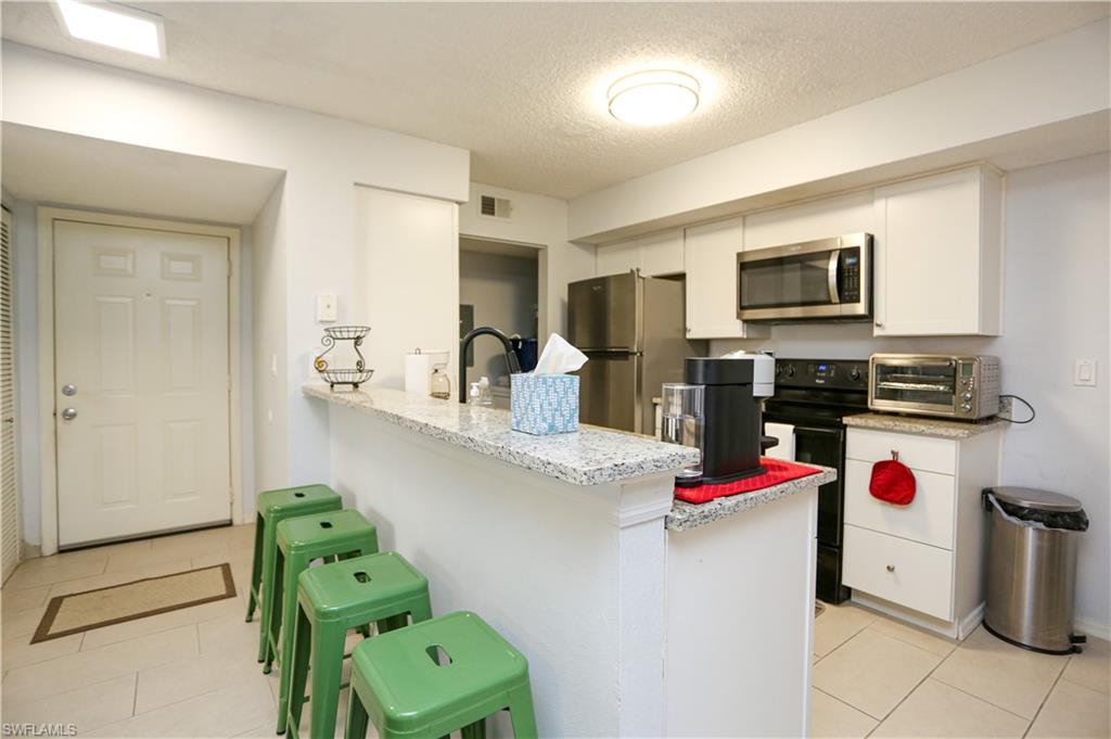 a kitchen with granite countertop kitchen island stainless steel appliances and a refrigerator