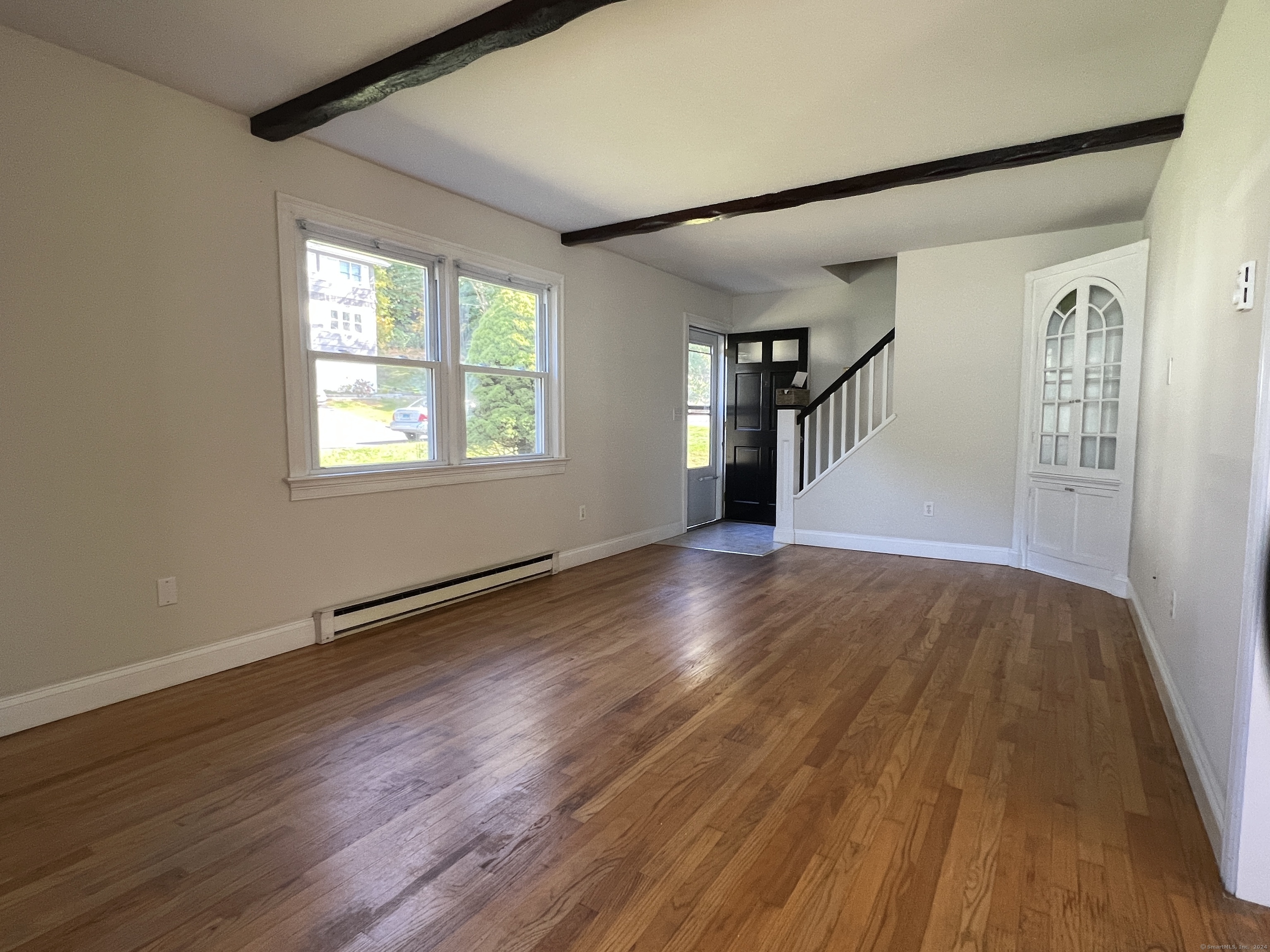 a view of an empty room with wooden floor and a window