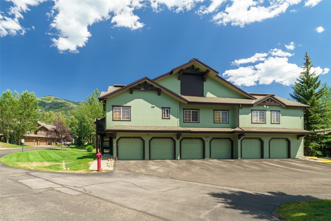 View of front of condo with a garage and a front lawn