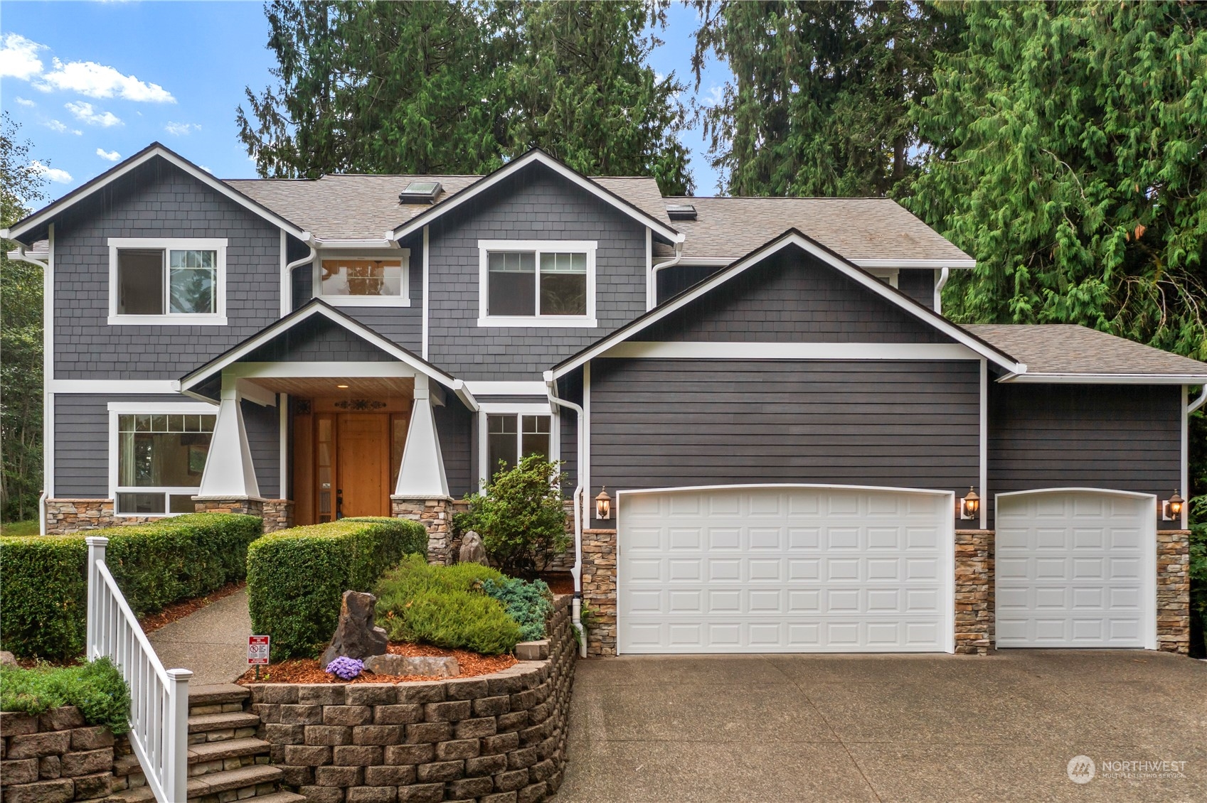 a front view of a house with plants and garage