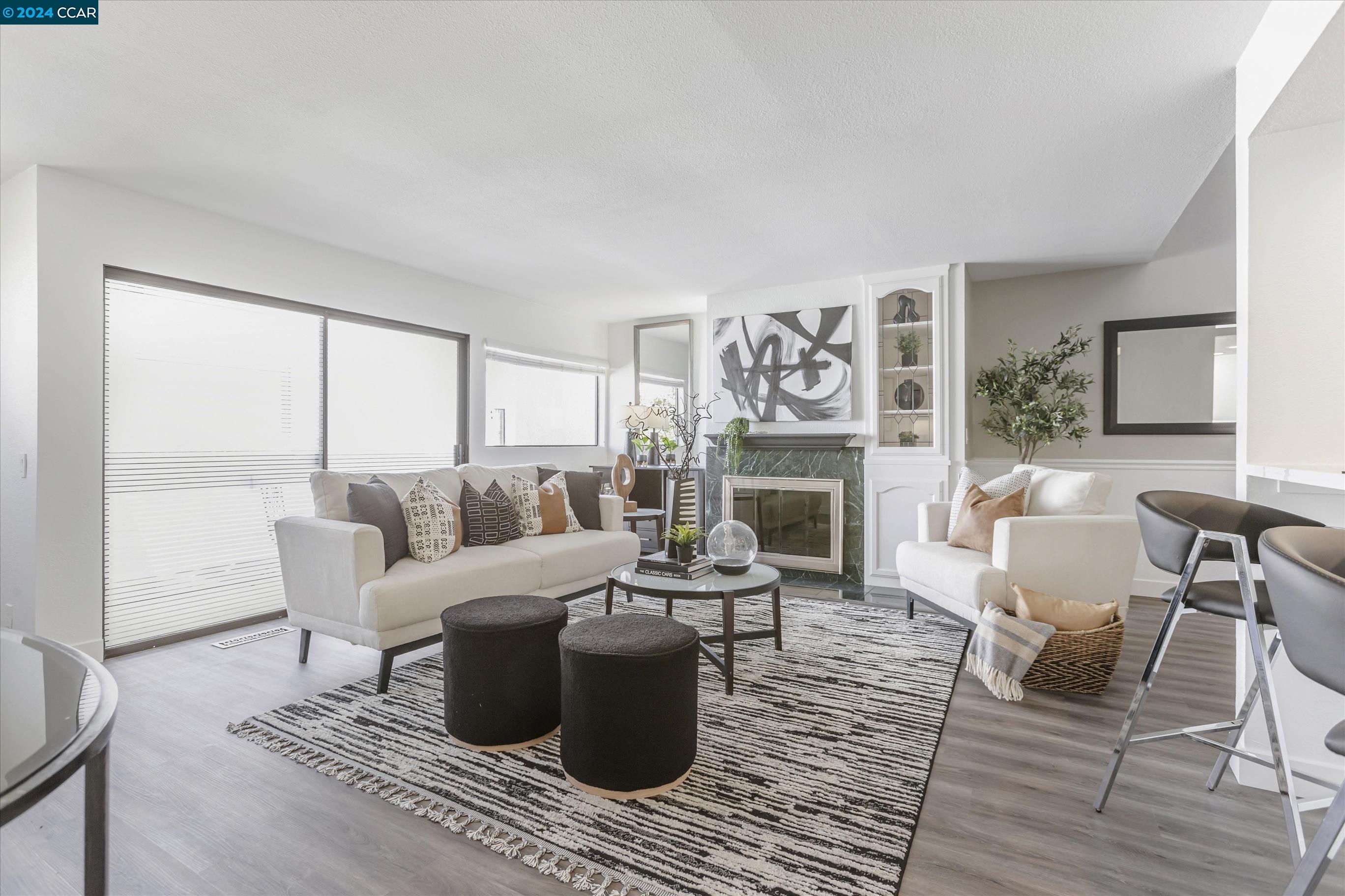 a living room with furniture large window and wooden floor