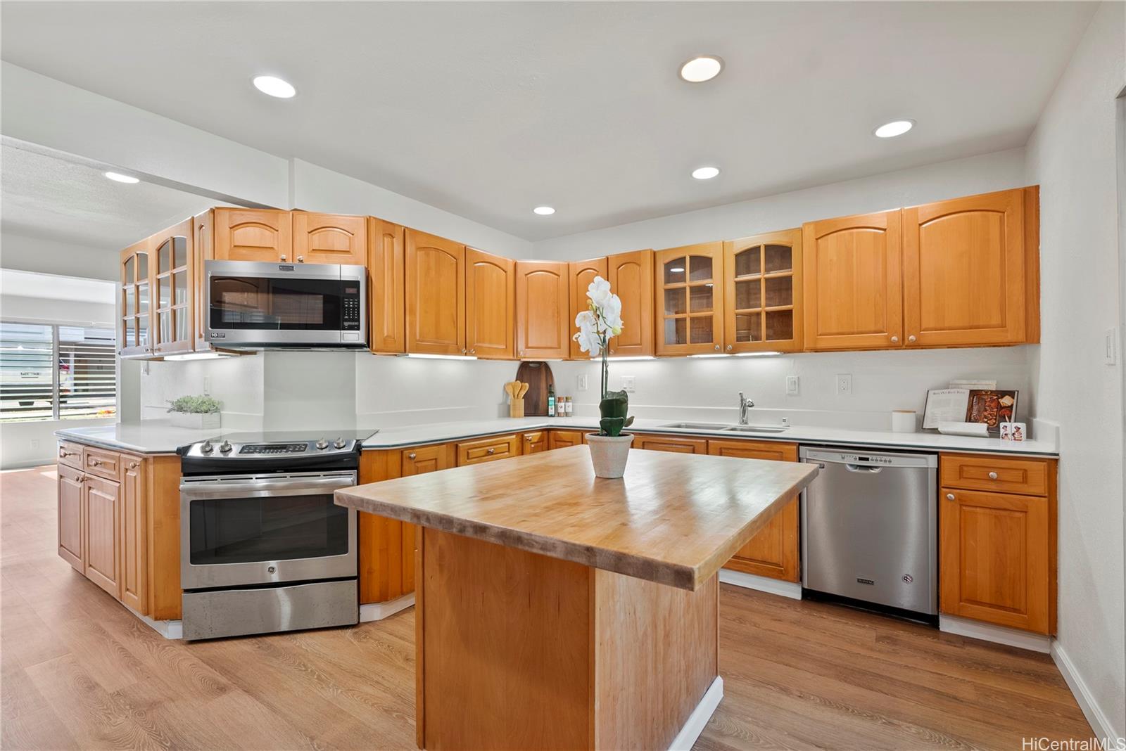 a kitchen with stainless steel appliances granite countertop wooden cabinets a sink dishwasher a stove and a refrigerator