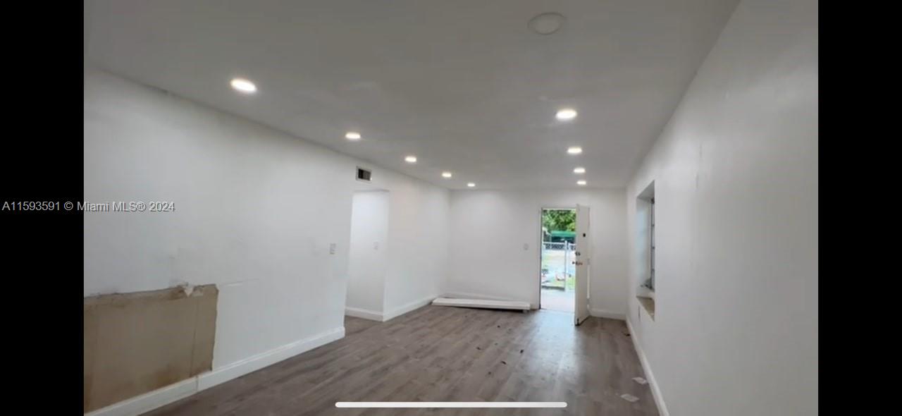 a view of an empty room with wooden floor and windows