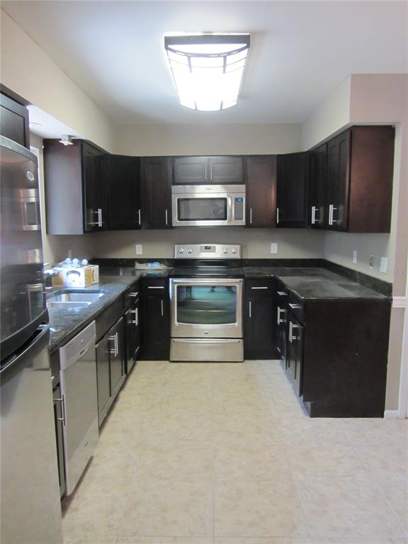 a kitchen with stainless steel appliances granite countertop a stove top oven a sink dishwasher and a microwave oven