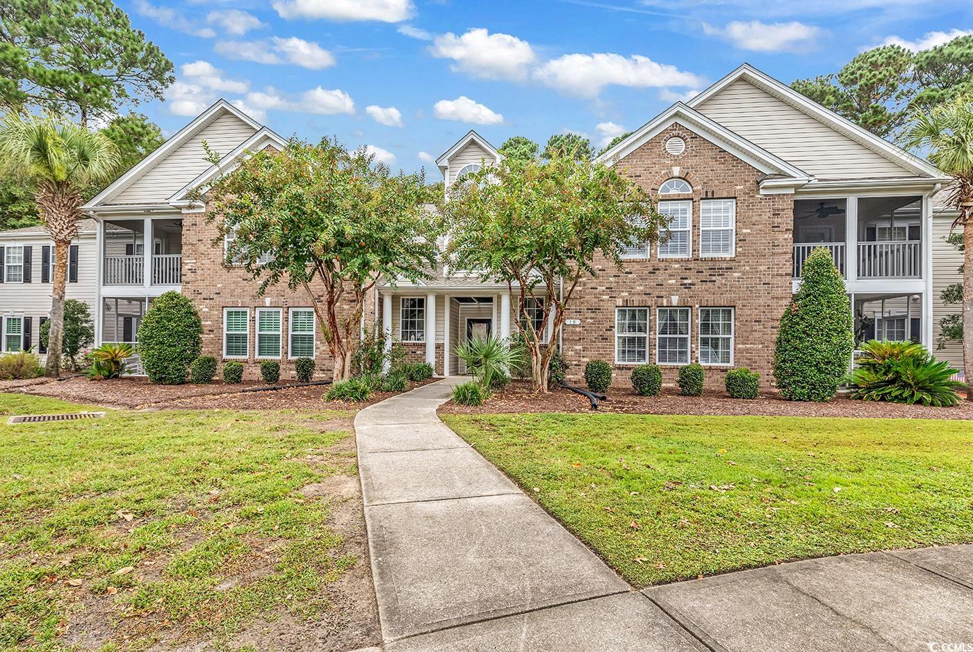 View of property with a front yard, a balcony, and