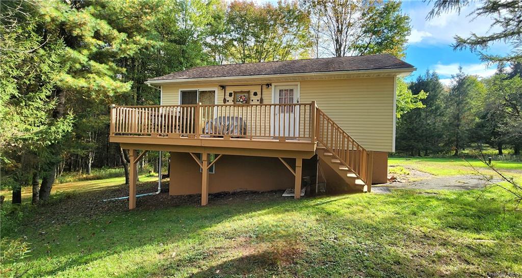 Rear view of property featuring a deck and a yard