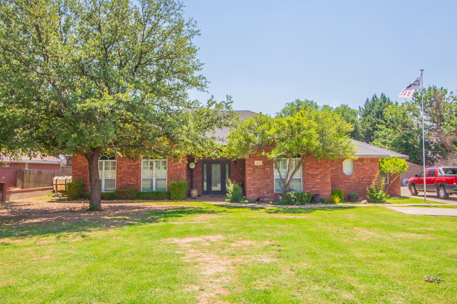 a front view of house with yard and trees in the background