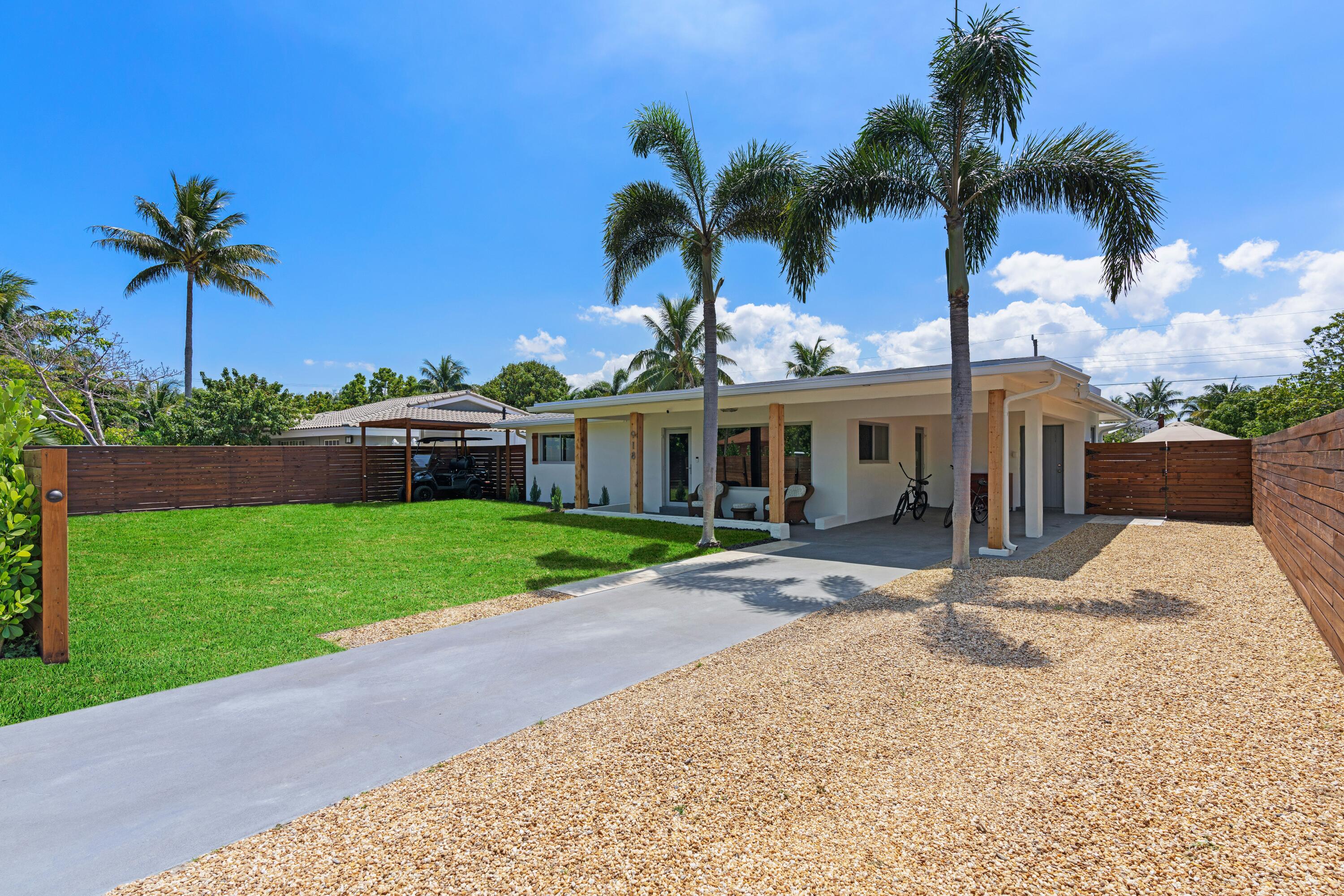 a view of a house with a yard and palm trees