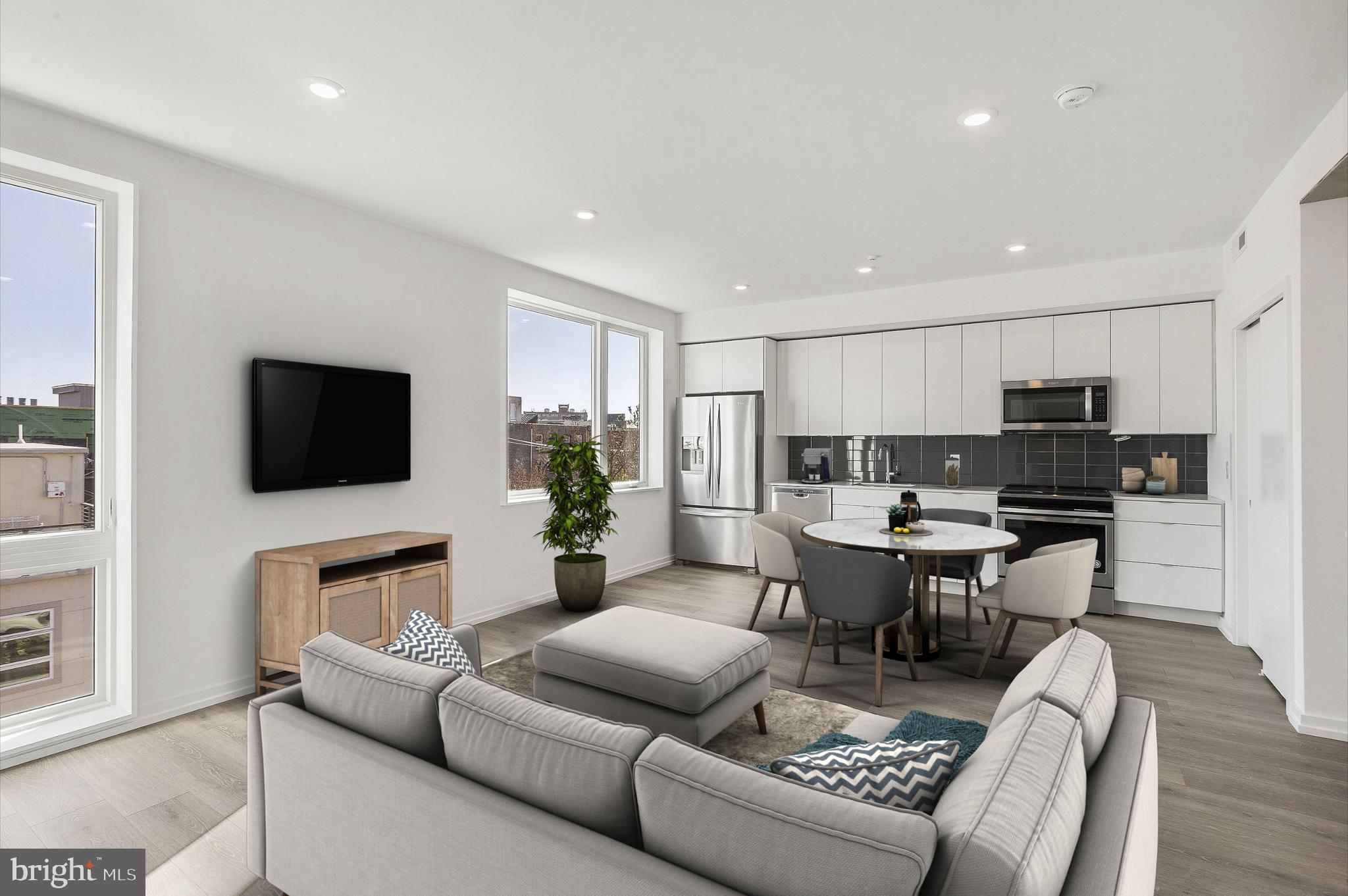 a living room with furniture a flat screen tv and kitchen view