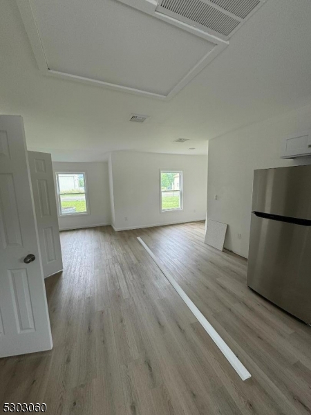 a view of empty room with window and wooden floor