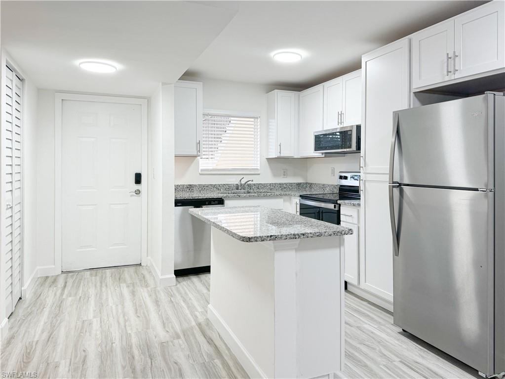 Kitchen with white cabinets, sink, stainless steel appliances, and light hardwood / wood-style floors