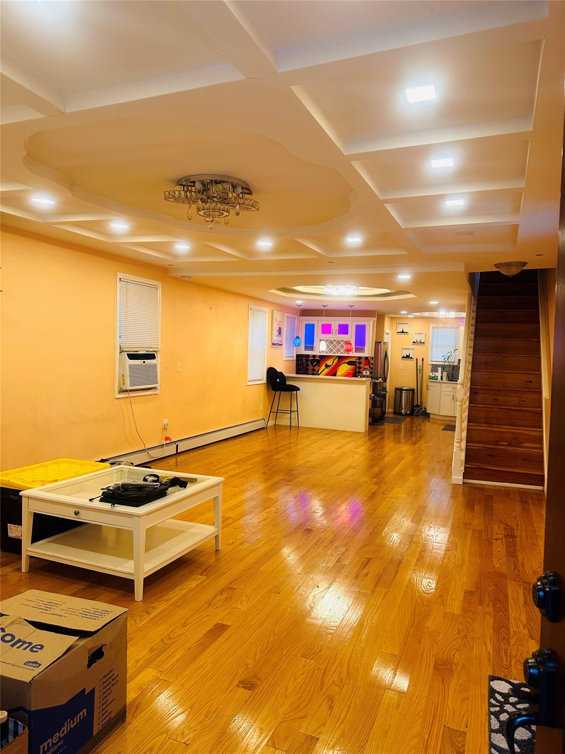 Miscellaneous room featuring cooling unit, wood-type flooring, coffered ceiling, and a baseboard radiator