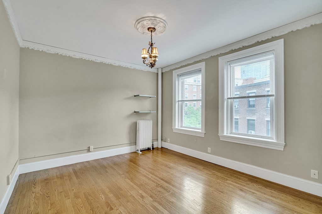 an empty room with wooden floor cabinet and windows