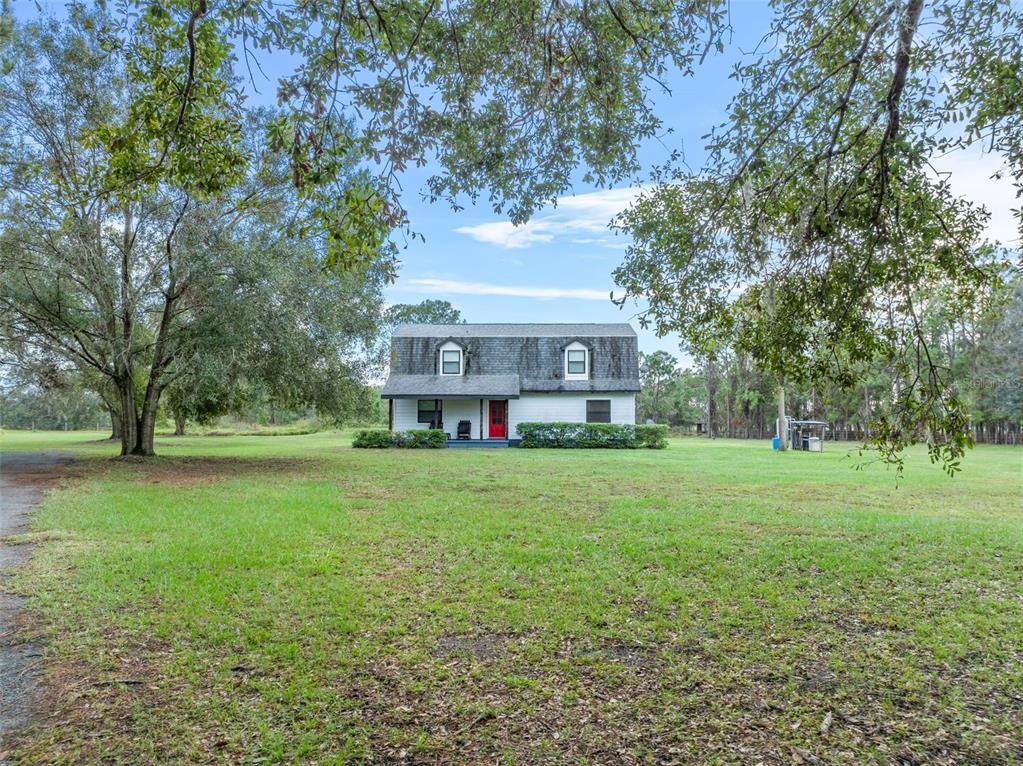 a view of a big house with a big yard and large trees