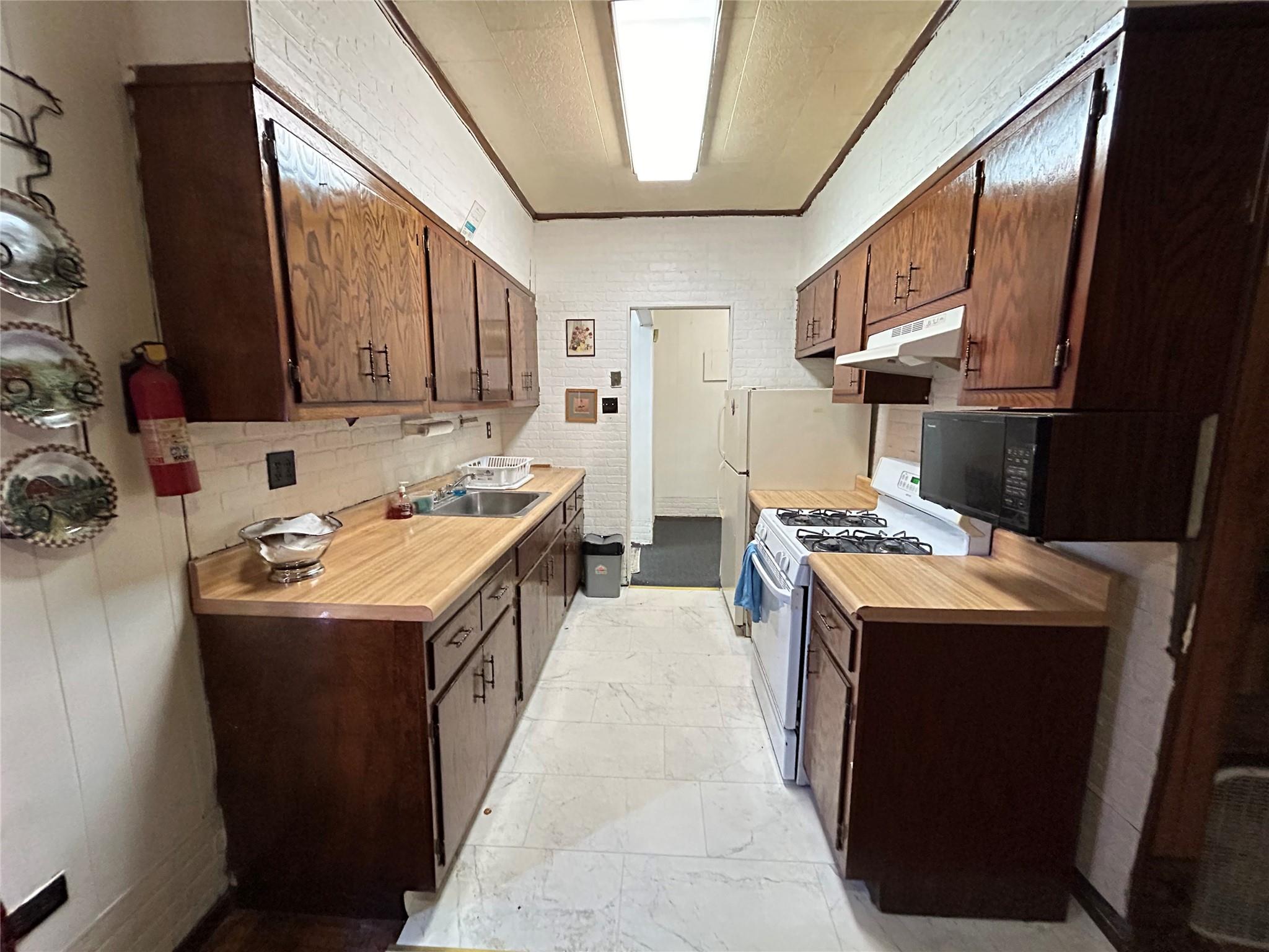 Kitchen featuring white range with gas stovetop, ornamental molding, and sink