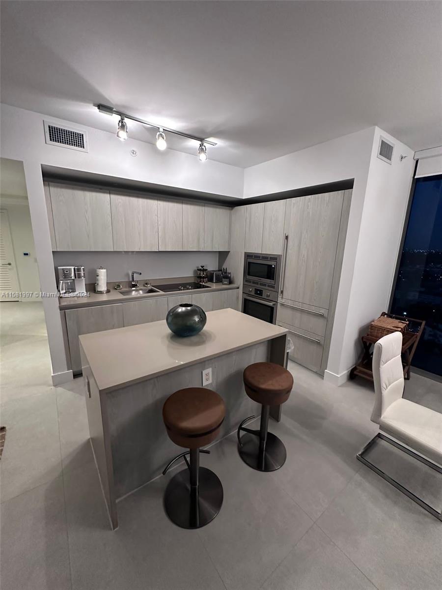 a kitchen with a sink a stove and chairs with wooden floor