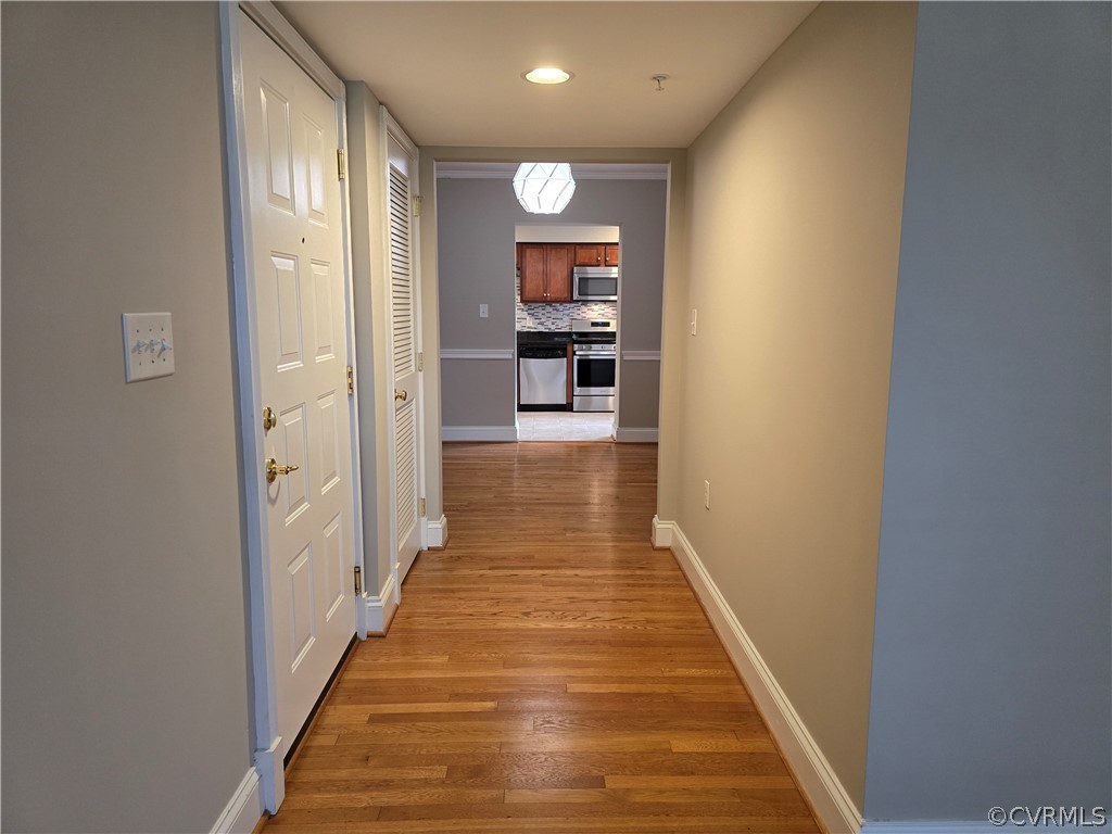 a view of a hallway with wooden floor and a bathroom