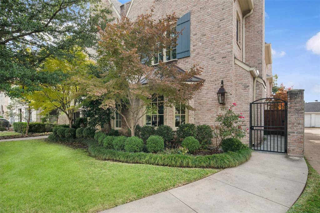 a view of a brick house next to a yard with potted plants and trees