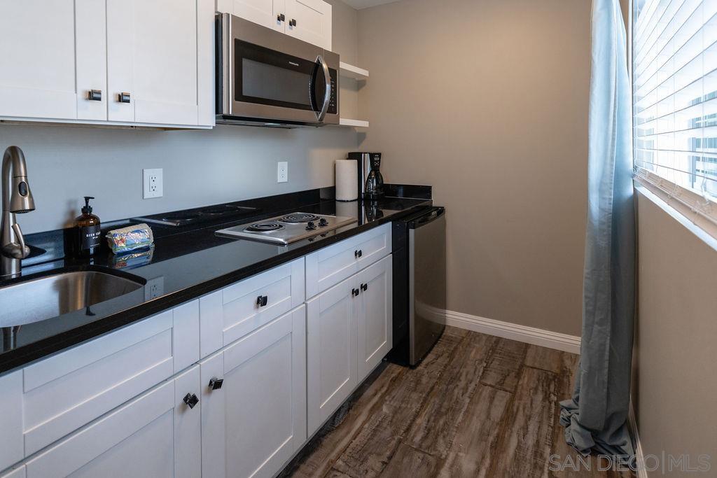 a kitchen with granite countertop white cabinets and black appliances